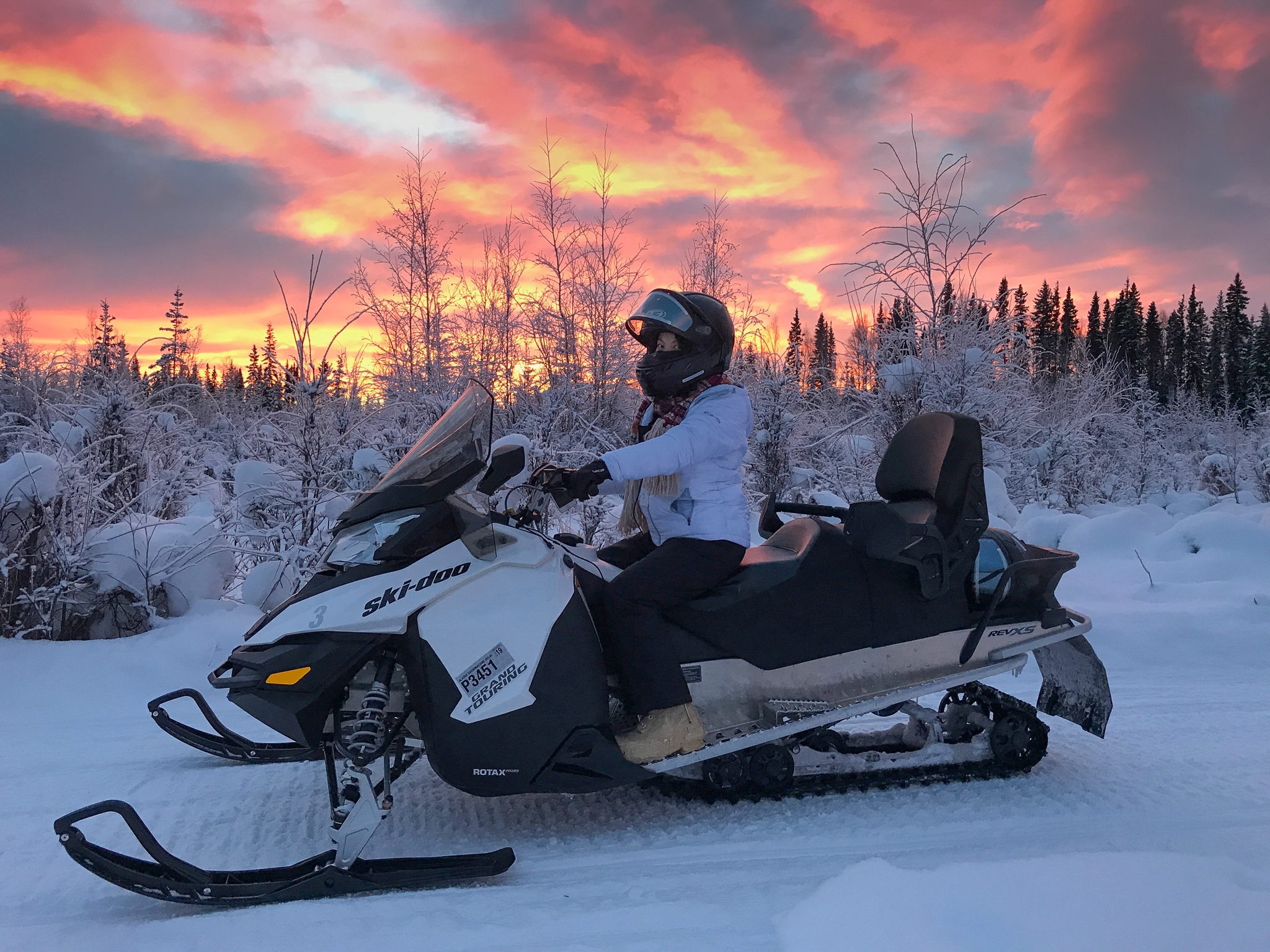 A man on a snow machine at sunset